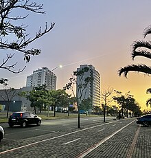 Imagem mostra avenida e edifícios de um bairro de Uberlândia ao entardecer.