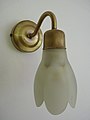 Messing wandlampje met een tulpvormig kapje van melkglas