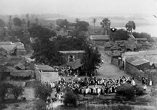 Photographie, vue en plongée d'un large cercle de personnes sur la place d'un village africain.