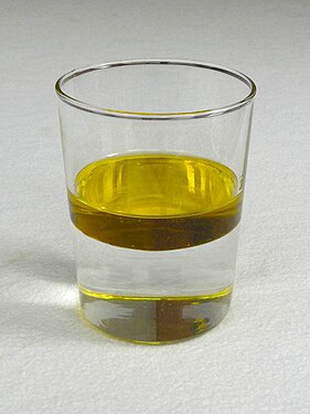Deux phases liquides en équilibre : de l'huile (jaune, en haut) sur de l'eau (transparente, en bas).