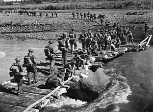 Australian troops cross a bridge over the 10-knot (19 km/h) Gusap River on 25 October 1943