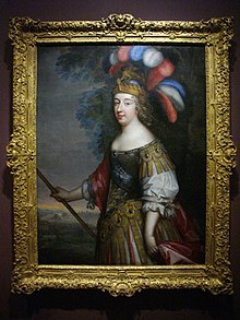 Photograph of an old portrait hanging in a frame on a wall showing a woman in armor, with a very large headdress of dyed peacock feathers and what might be a spear