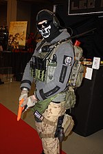 Man dressed up as the fictional character Simon "Ghost" Riley wearing skull print balaclava, blacked out glasses and army equipment.