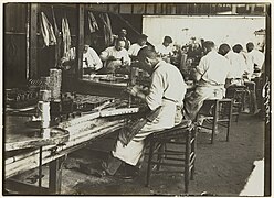 Photographie montrant des ouvriers travaillant dans une sardinerie bretonne (photographie par Paul Géniaux, conservée au Musée de Bretagne à Rennes).