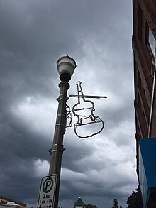 Fiddle decoration that is an outline of the instrument hanging from a light post on a street in Shelburne, Ontario.