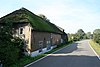 Boerderij, evenwijdig aan de dijk gebouwd onder rieten wolfdak. Rechts de stal, opgetrokken van gepotdekselde houten delen. In het woongedeelte een sieranker en twee vensters met 12-ruitsroedenverdeling in de ramen