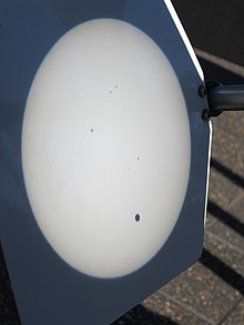 White disk with a small black dot projected on a screen
