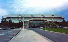 An arena is situated behind an empty parking lot.