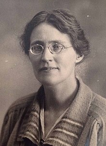 Molly Crowfoot. Schwarz-Weiß-Porträt einer Frau in Wolljacke mit runder Brille.