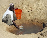 Νερόλακος στο χωριό Μουαμανόνγκου (Mwamanongu), στην Περιοχή Μεάτου (Meatu), στην Περιφέρεια Σινυάνγκα (Shinyanga), Τανζανία. Το νερό προέρχεται συνήθως από ανοικτές τρύπες, σκαμμένες στην άμμο των ξεροπόταμων και είναι κατά κανόνα μολυσμένο.