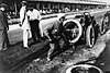 While three men stand by watching, a fourth man hurries to collect a spare tyre and change it onto his open-topped car.