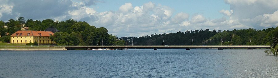 Drottningholmsbron i augusti 2012 sett från Kärsön. Den gula byggnaden vid vänstra brofästet är Hertigarnas stall.