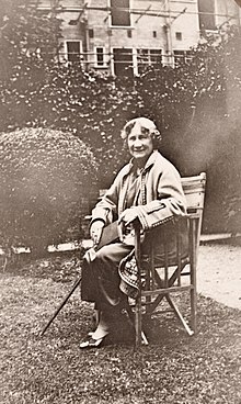 Hull sitting on a folding chair in a garden, she is holding a cane.