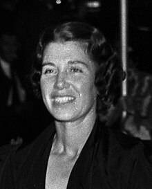 Head-and-shoulders photo of a smiling Caucasian woman with wavy, shoulder-length dark hair