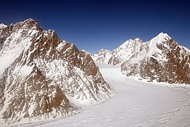 Photographie aérienne et en couleurs d'une vallée glaciaire traversant un massif montagneux.