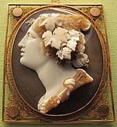 Black and white stone cameo of a woman facing left with flowers and leaves in her hair