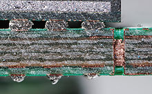 Cut through a SDRAM-module, a multi-layer PCB (BGA mounted). Note the via, visible as a bright copper-colored band running between the top and bottom layers of the board. Bga und via IMGP4531 wp.jpg