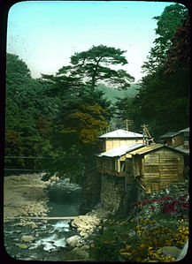 Buildings built up on stone walled riverbank with trees in background