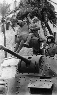 Parade of Italian forces alongside an equestrian statue of Mussolini during the North African campaign in Tripoli, Italian-occupied Libya (Bundesarchiv Bild, March 1941) Bundesarchiv Bild 183-B11231, Nordafrika, Truppenparade in Tripolis.jpg
