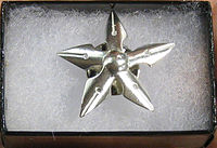 A five-pointed star pin made of fountain pen nibs resting in a small box