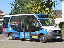 Photographie en couleurs d’un minibus multicolore, mais majoritairement bleu, blanc et noir.