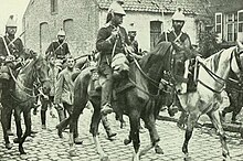 Photo noir et blanc d'un petit groupe de fantassins entouré de cavaliers, portant le sabre ou le pistolet.