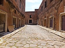 Tabernae along Via Biberatica Mercati at Trajan's Market in Rome, shops at the right with replica shutters Markets of Trajan -- Via Biberatica (14673711087).jpg