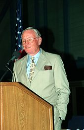 Photo of Armstrong speaking at a podium.