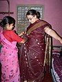 This woman is helping a girl put on a type of wrap called a sari