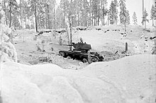 Советский легкий танк, если смотреть с его левой стороны, описан финским фотографом как агрессивно наступающий в заснеженном лесном ландшафте во время битвы при Коллаа.