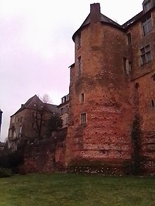 Vue d'une tour percée de fenêtres à partir de la droite et accolée à un édifice