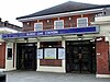 A red-bricked building with a blue sign reading "BURNT OAK STATION" in white letters and four surveillance cameras in front of the doors