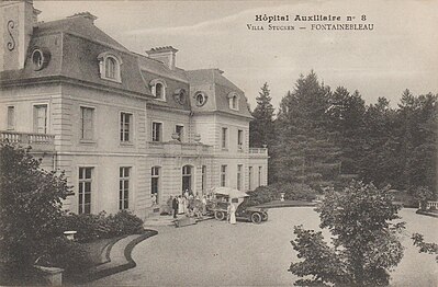 Une ambulance et du personnel stationnés sur le perron de la villa dans la cour d’Honneur durant la Première Guerre mondiale.