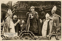 King Charles IV, taking his coronation oath at Holy Trinity Column outside Matthias Church (1916). To date, he is the last monarch to be crowned with St. Stephen's Crown. Notice the size difference between the crown and the king's head. Karloath.jpg