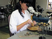 Master engraver ennobling a watch movement. Top-level engravers work under a stereo microscope. Louis George Meistergraveurin 2.jpg