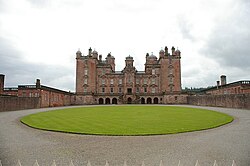View of the front of Drumlanrig Castle, looking slightly up, standing near the fencing separating the castle itself from the public