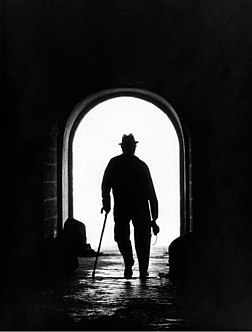 Silhouette en contre-jour d’un homme marchant avec une canne dans un tunnel, appareil photo en main. À Alcobaça, dans la baie de São Martinho do Porto (Portugal). (définition réelle 1 311 × 1 729)