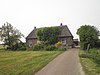 "De Tempel," boerderij met dwars woonhuis onder een met riet gedekt schilddak. Schuifvensters met strekken en roedenverdeling en met luiken behangen. Rechts opkamer. Zolderluiken. Pomp