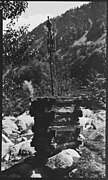 : Rumbur Valley, Chitral, NWFP, Pakistan. Kalasha ancestral tutelary effigy (kundurik, gundik) protecting the fields. A male figure sitting on a chair is crowning the top of a carved wooden pole. The pole is fixed in the middle of a wooden structure filled with stones.