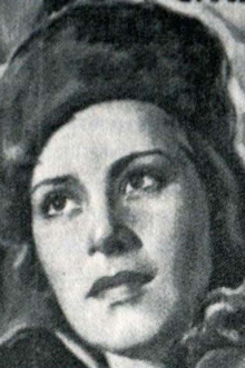 Black and white image of a woman wearing an ushanka, facing toward the camera and slightly to the viewer's right, her gaze tilted upward.
