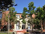 An exterior shot of a red brick building behind several trees.