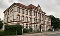 Schule mit Einfriedung und Gehwegpflasterung vor dem Schuleingang (ehemals Realschule und Berufliches Schulzentrum Haus II, heute Regenbogen-Grundschule)