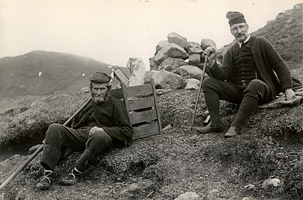 Overlærer Louis Bergh (no) og ledsager, der bærer rygkurven − Hvilepause under fjeldvandring