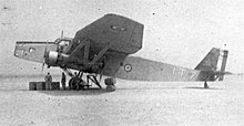 Photo d'un avion posé sur un terrain, de profil, avec cocardes tricolores.