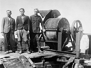 Members of a Sonderkommando 1005 unit pose next to a bone crushing machine in the Janowska concentration camp.png