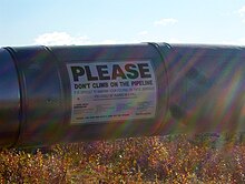 Photo d'une plaque apposée sur l'oléoduc avec un message d'avertissement.