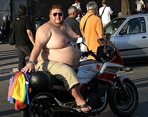 An obese topless man on a motorcycle. Original...