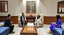 Photographie d'une rencontre officielle entre quatre personnes assises sur des fauteils.