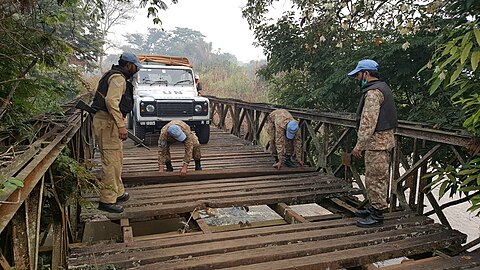 Photographie de soldats aux casques bleus en cours de réparation d'un pont pour y faire passer un véhicule.