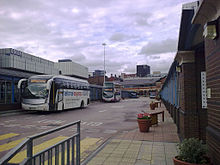 Sheffield Interchange, the main hub for bus and coach operations in Sheffield. Visible are two of the main sections of the interchange containing numerous bus stops. Also visible is the Archway centre (centre-background)which contains shops, offices etc. In the centre are several buses and a National Express coach.